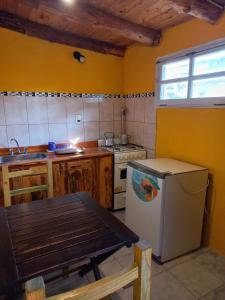 uma cozinha com uma mesa, um fogão e um lavatório em Cabañas Los Nonos em El Bolsón