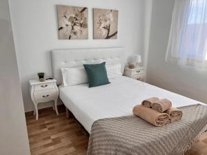 una camera da letto con un letto bianco con asciugamani sopra di Apartamento Marae a Corralejo