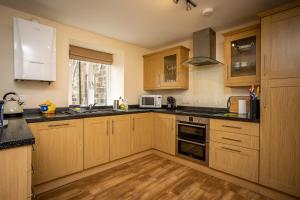 a kitchen with wooden cabinets and black counter tops at Swallow View, A Spacious Base with stunning views in Matlock