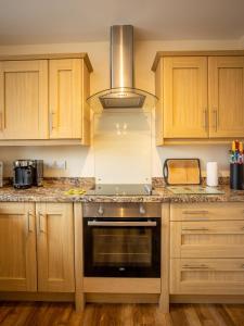 a kitchen with wooden cabinets and a stove top oven at Swallow View, A Spacious Base with stunning views in Matlock