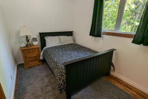 a bedroom with a bed with a black bed frame and a window at Cozy Cabin on Trout Lake in North Bay