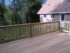 a wooden deck in front of a house at Cozy Cabin on Trout Lake in North Bay