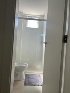 a white bathroom with a toilet and a shower at Apartamento à 380m do Mar in Itapema