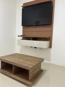 a flat screen tv on a wall with a coffee table at Apartamento à 380m do Mar in Itapema