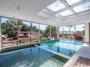 een binnenzwembad in een huis met ramen bij Apartamento Bellagio 2 Suítes e Piscina by Achei in Canela