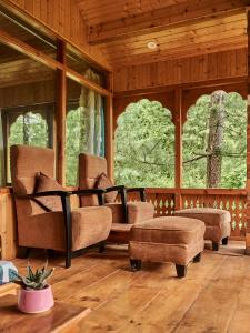 a living room with chairs and a couch and windows at The Lazy and Slow in Nagar