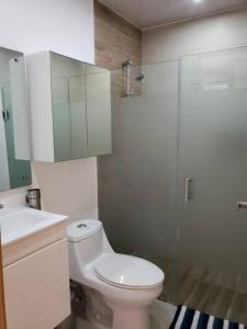 a bathroom with a toilet and a glass shower at Boca Del Mar, Torre l, Apto. 412 in Boca Chica