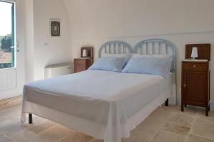 1 dormitorio con 1 cama blanca grande con almohadas azules en Masseria del Poeta by BarbarHouse, en Ceglie Messapica