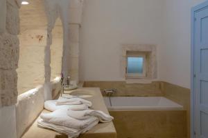 y baño con lavabo, bañera y toallas. en Masseria del Poeta by BarbarHouse, en Ceglie Messapica