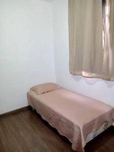 a small bed in a room with a window at Apartamento para Temporada, sem vaga de garagem! in Belo Horizonte