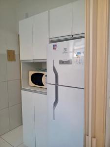 a white refrigerator in a kitchen with a microwave at Apartamento para Temporada, sem vaga de garagem! in Belo Horizonte
