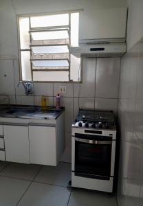 a small kitchen with a stove and a window at Apartamento para Temporada, sem vaga de garagem! in Belo Horizonte