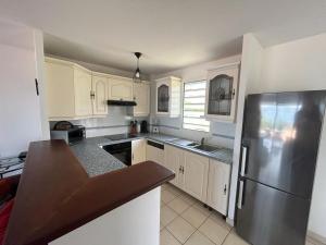 a kitchen with white cabinets and a stainless steel refrigerator at Les Tuileries in Les Trois-Îlets