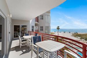 uma varanda com mesas e cadeiras e a praia em 203 Crimson Condos em St. Pete Beach