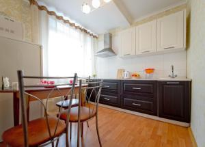 a kitchen with white cabinets and a table and chairs at Five Stars Comfort in Chelyabinsk