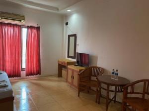 SukaramiにあるBelvena Makati Hotelのリビングルーム(テレビ、テーブル、椅子付)