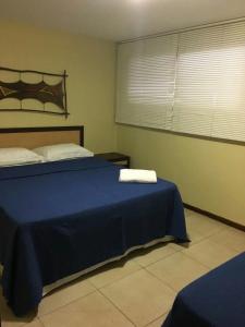um quarto com uma cama azul com duas toalhas em Dúplex 2 quartos no coração de Pipa em Pipa