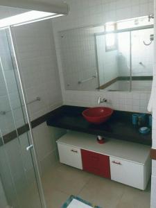uma casa de banho com um lavatório vermelho e um espelho. em Dúplex 2 quartos no coração de Pipa em Pipa