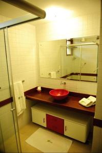 uma casa de banho com um lavatório vermelho e um espelho. em Dúplex 2 quartos no coração de Pipa em Pipa