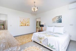 a white bedroom with a bed and a chandelier at Pamatai Chill House in Faaa