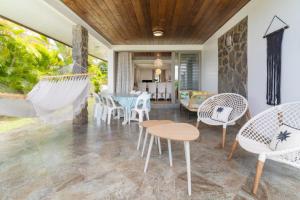 eine Terrasse mit Stühlen, einem Tisch und Hängematten in der Unterkunft Pamatai Chill House in Faaa