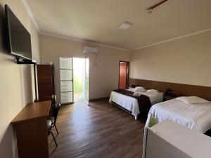 a hotel room with two beds and a flat screen tv at Hotel Elithi - O melhor custo benefício in Itapeva