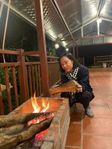 a woman sitting next to a fire pit at Lanh Sapa Homestay in Sa Pa
