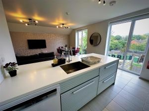 a kitchen with a sink and a living room at Horizon House, Modern 2-Bedroom Flat 2, Parking, Netflix, Oxford in Oxford