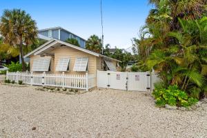 a house with a white fence and palm trees at The Seashell Cottage in Anna Maria
