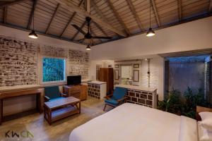 a bedroom with a bed and two chairs and a television at Tranquilla in Nikapota