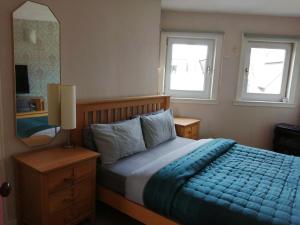 um quarto com uma cama com um edredão azul e 2 janelas em Aigas em Glasgow