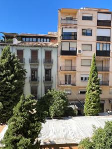 un edificio alto con árboles delante de él en Suite Catedral, en Granada