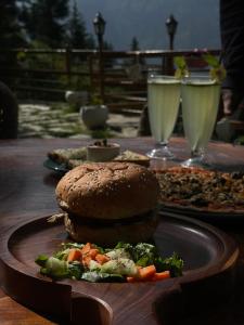 einen Tisch mit zwei Tellern Essen und zwei Getränken in der Unterkunft The Lazy and Slow in Nagar