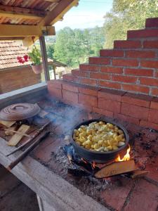 una olla de comida sobre un fuego en una parrilla en Seosko domaćinstvo Alababa en Kosjerić