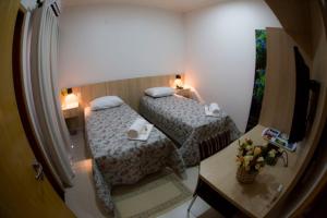 a small room with two beds and a table at Hotel San Gennaro in Santa Fé do Sul