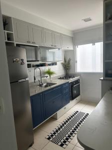 uma cozinha com armários azuis e um lavatório em Apartamendo na Enseada em Ubatuba
