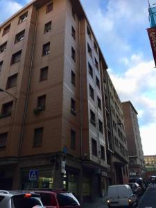 un edificio alto con coches estacionados frente a él en Amplio, luminoso y moderno cerca del Casco Viejo en Bilbao