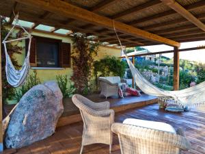 a porch with a hammock and chairs and a rock at Smart Appart Sweet Sardinia in Murta Maria