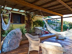 ポルト・サン・パーオロにあるSmart Appart Sweet Country House Sardiniaのハンモックと椅子と岩のあるポーチ