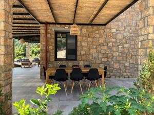 a stone walled patio with a wooden table and chairs at The Mavrolitharo Residence in Akti Salonikiou