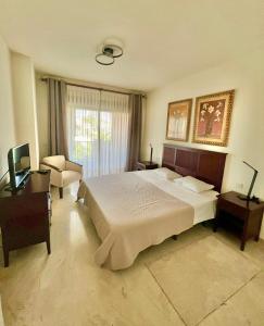 een slaapkamer met een groot bed en een stoel bij Apartment next to the El Campanario, Atalaya Golf in Estepona