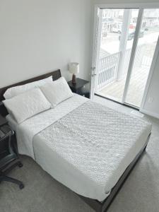 1 dormitorio con cama blanca y balcón en 2 bedroom ensuite, en Stittsville