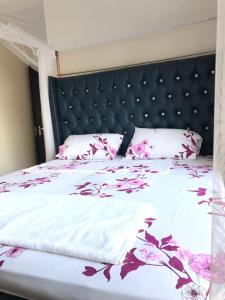 um quarto com uma cama com flores cor-de-rosa em Vipingo Palm - 3BDR Apartment em Vipingo