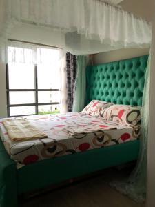 a bedroom with a bed with a green headboard and a window at Vipingo Palm - 3BDR Apartment in Vipingo