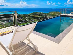 una silla en el balcón con vistas al océano en Villa Grand Horizon with extraordinary 180 degree sea view, en Saint Martin