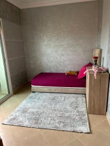 een kleine slaapkamer met een bed en een tapijt bij Super appartement in Aïn ej Jmel