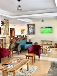 a living room with couches and tables and a tv at The Address Resort in Kalangala
