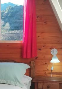 1 dormitorio con ventana y cortina rosa en Cabañas en Koslay en Juana Koslay 