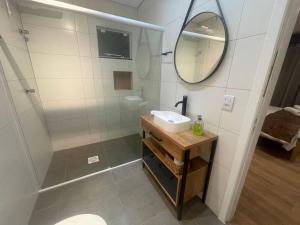 uma casa de banho com um chuveiro, um lavatório e um espelho. em Casa Enxaimel 02 em Pomerode em Pomerode