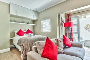 a bedroom with a bed with red pillows and a couch at Fairmile on Main in Cape Town